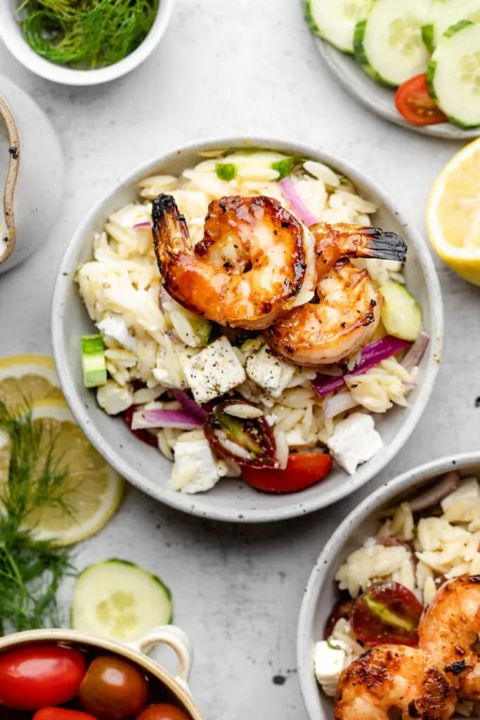 two pieces of shrimp on top of orzo salad