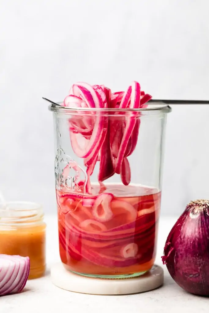 pickled onions on fork in jar