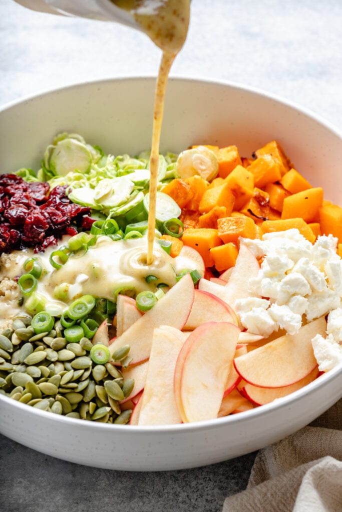 apple cider dressing being poured on salad