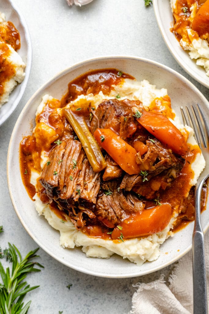 dutch oven pot roast in bowl over mashed potatoes
