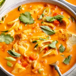 red curry chicken soup in bowl with spoon