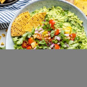 guacamole in bowl with topping and tortilla chips