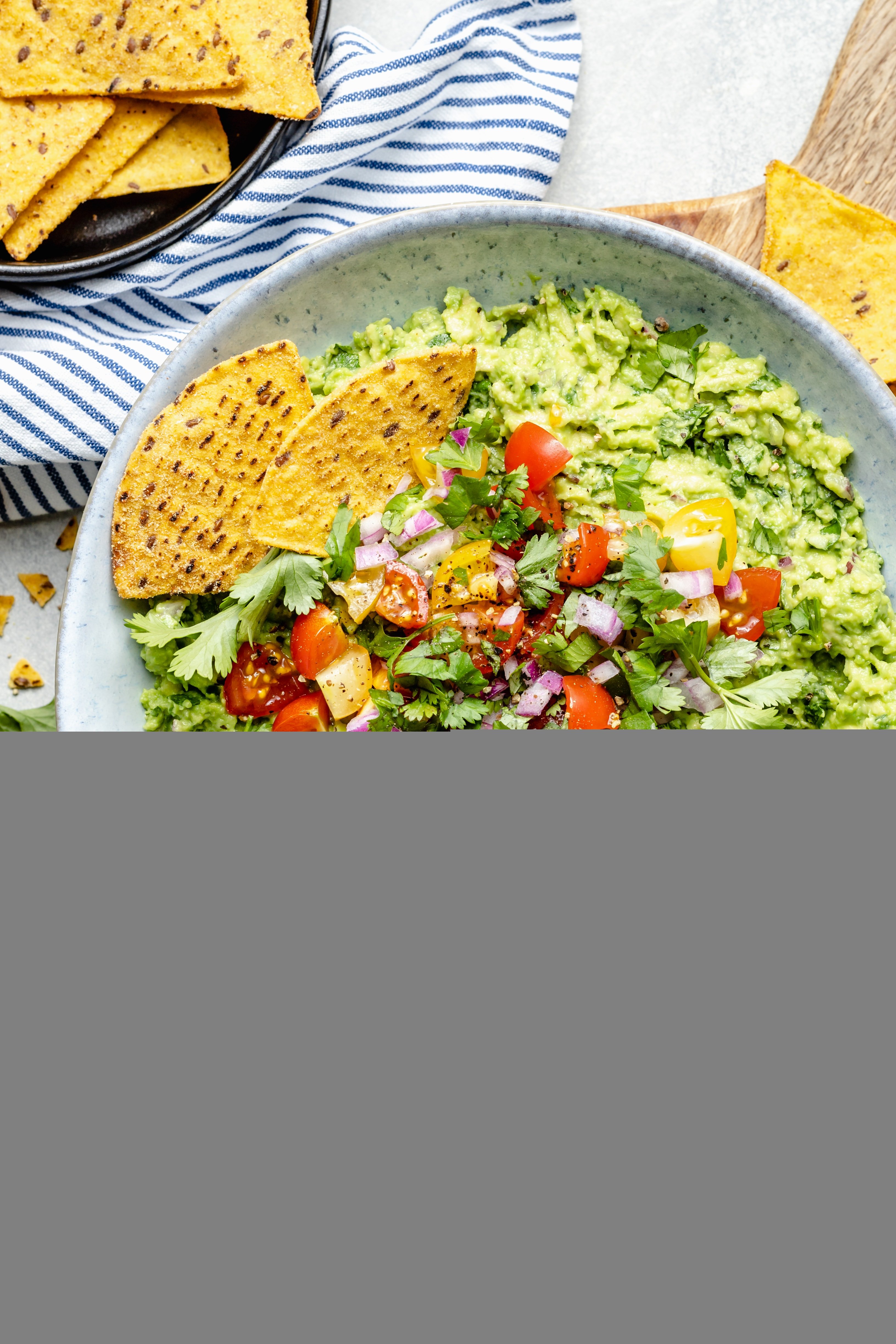 guacamole in bowl with topping and tortilla chips