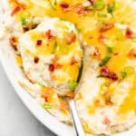 loaded mashed cauliflower with spoon in casserole dish