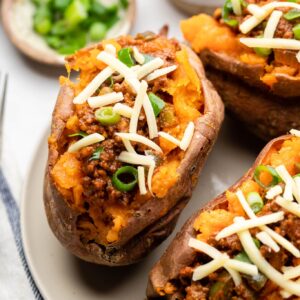 stuffed sweet potato sloppy joes on plate with shredded cheese