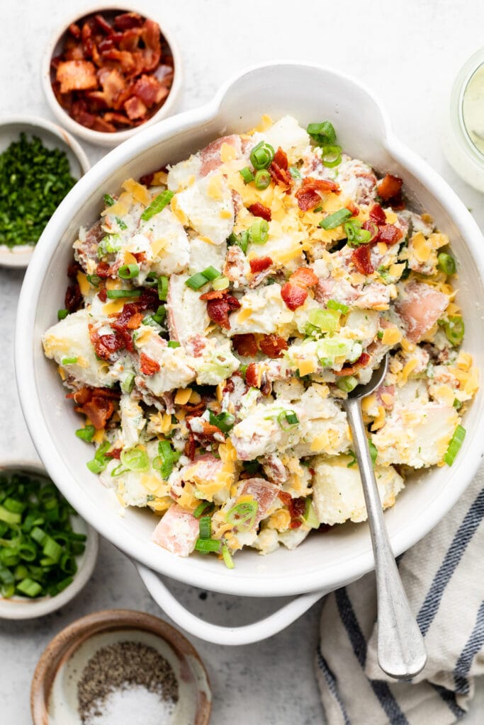 loaded baked potato salad in bowl with spoon