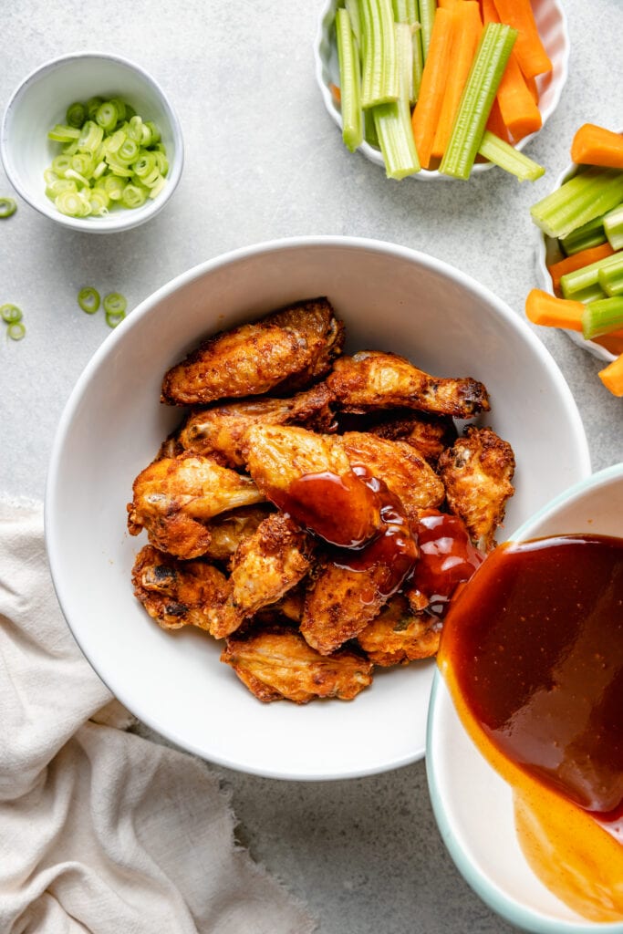 sauce being poured over wings