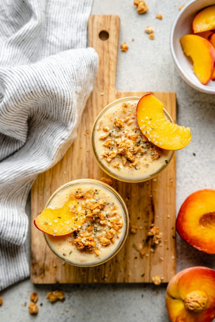 creamy peach smoothie topped with granola and peach