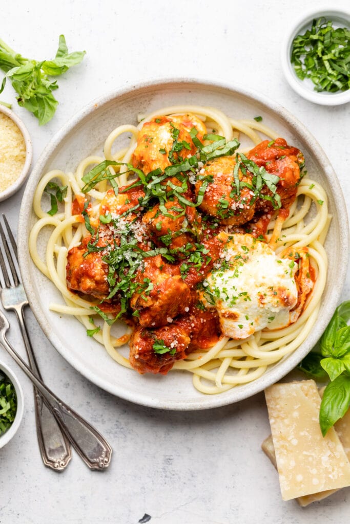 chicken parmesan meatballs over pasta in bowl
