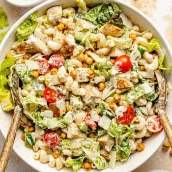 chicken caesar pasta salad in bowl with serving spoons