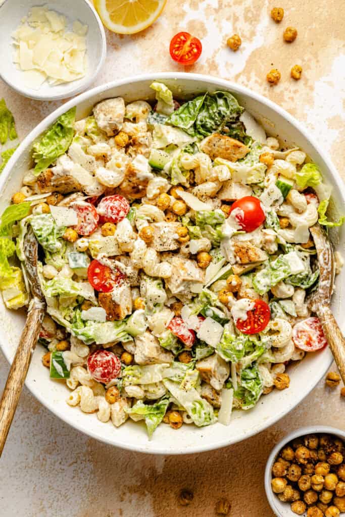 chicken caesar pasta salad in bowl with serving spoons