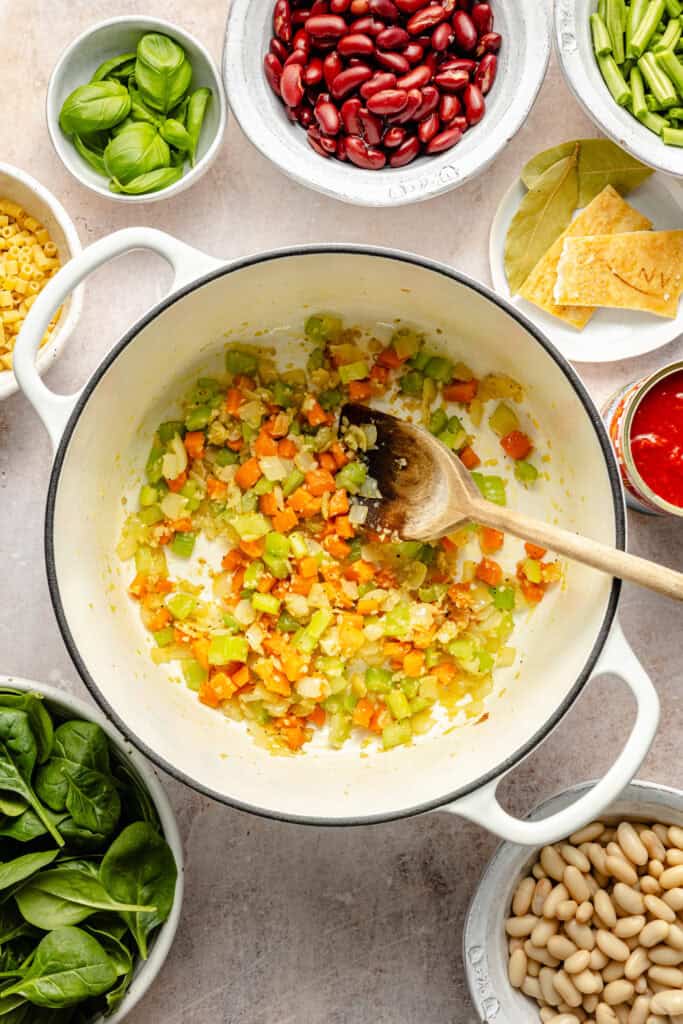 celery, onion, and carrot sautéed in pot with wooden spoon