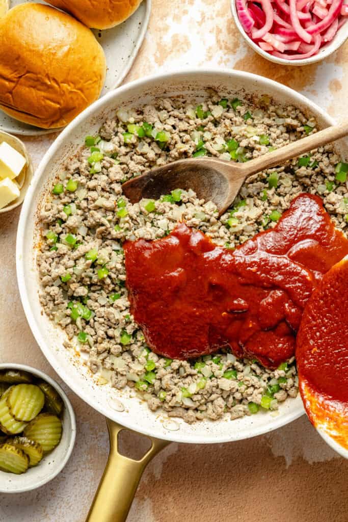 pouring sloppy joe sauce over meat and veggies