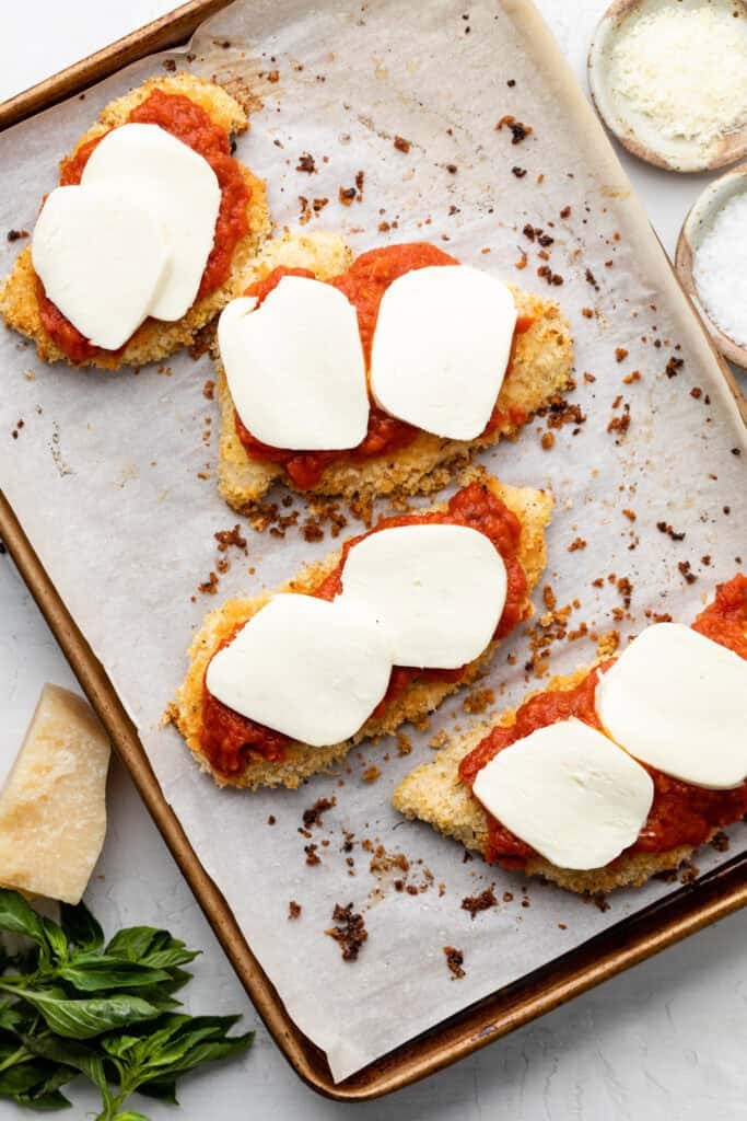 chicken coated in marinara sauce with slices of mozzarella