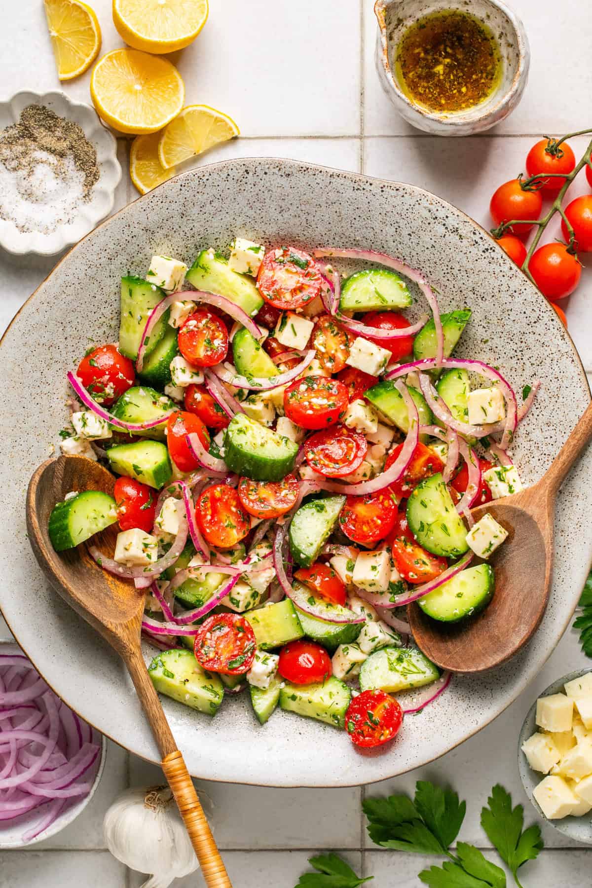 cucumber tomato salad in serving bowl with wooden spoons