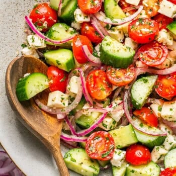 cucumber tomato salad in bowl with wooden spoon