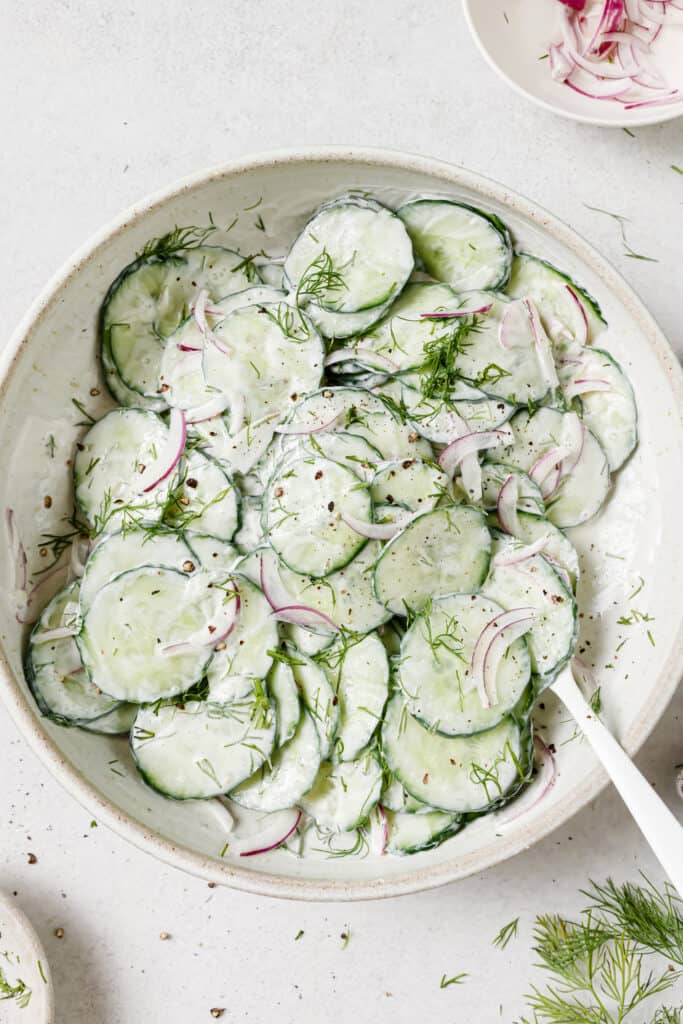 creamy cucumber salad in bowl with spoon