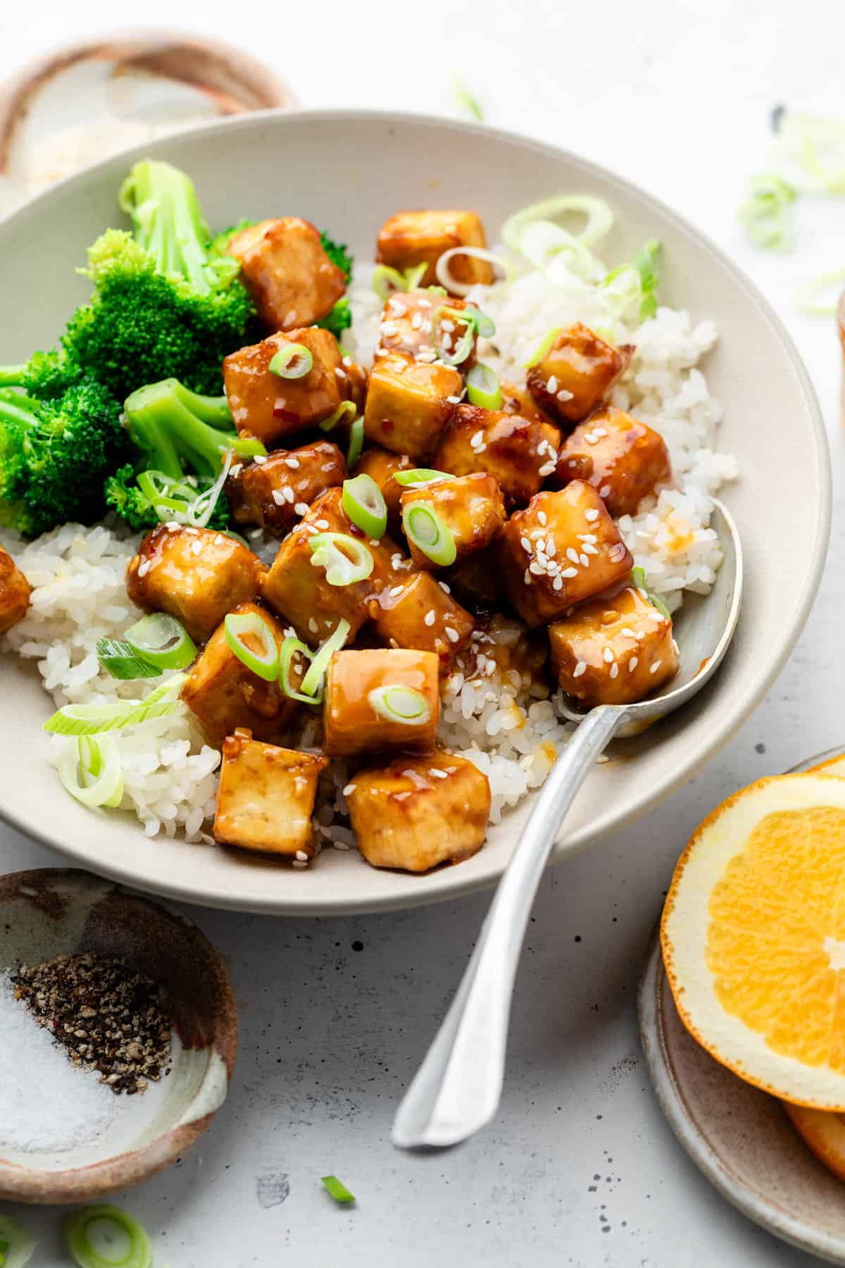 orange tofu with rice broccoli and spoon