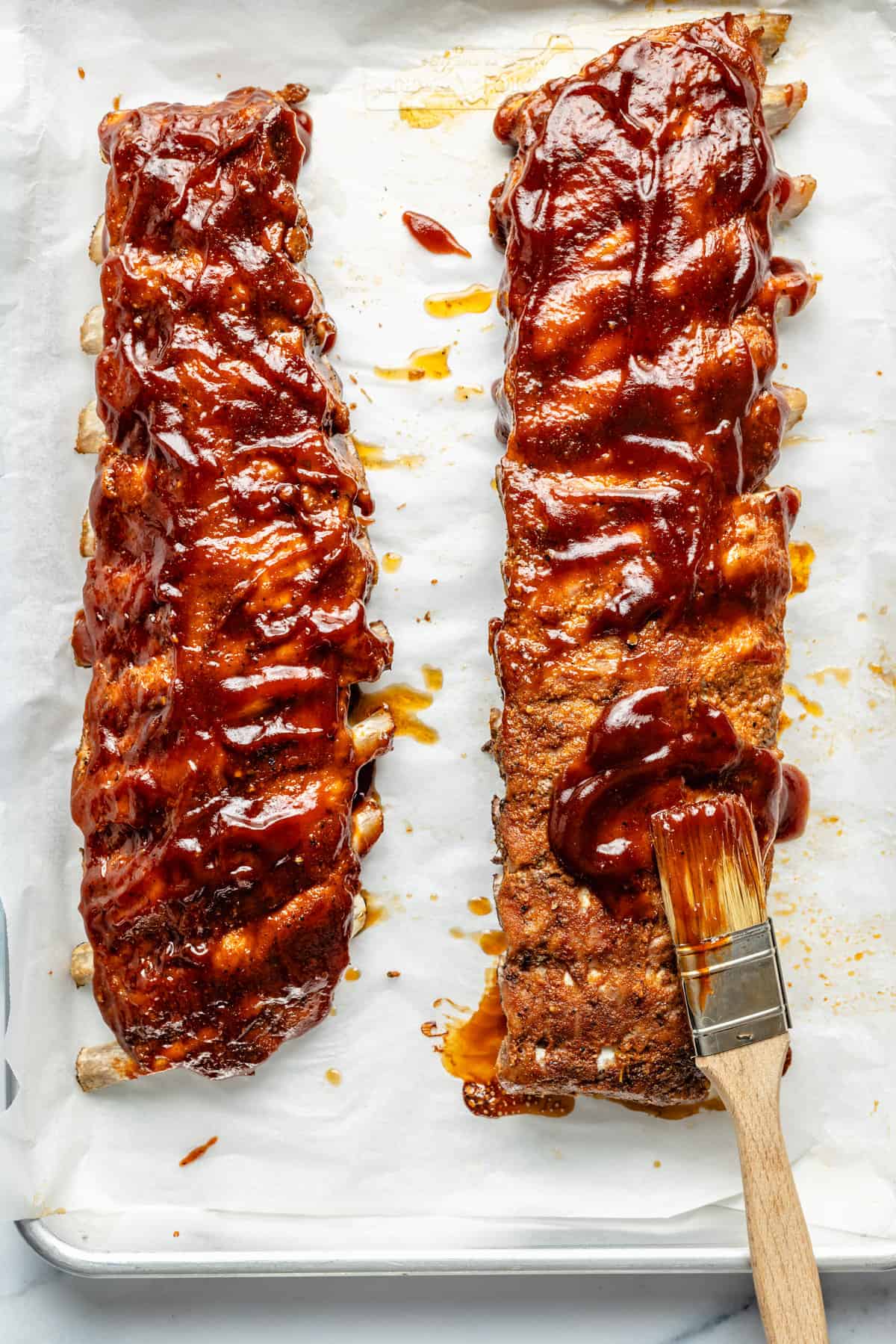 barbecue sauce being spread on ribs