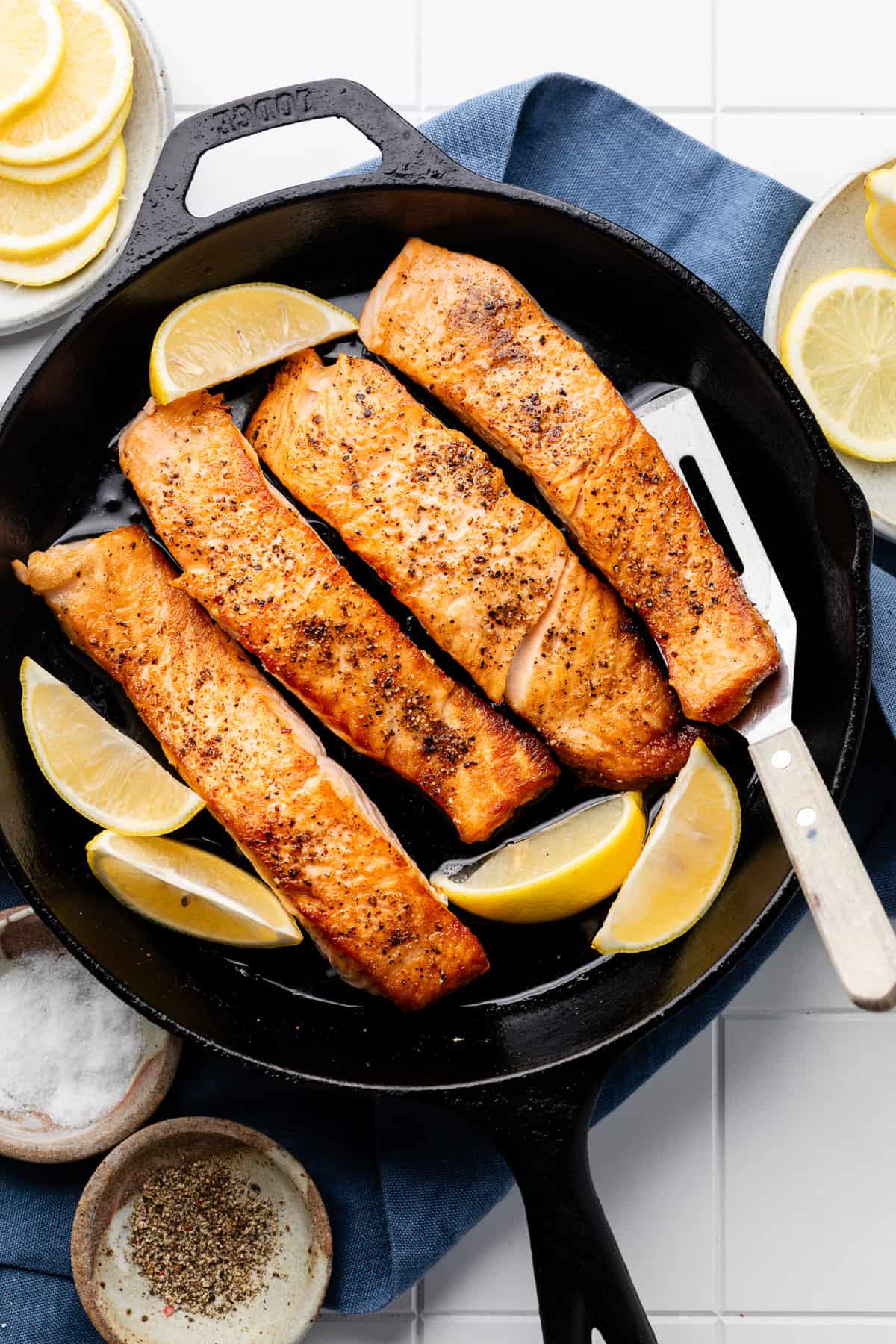 salmon in skillet with lemon wedges