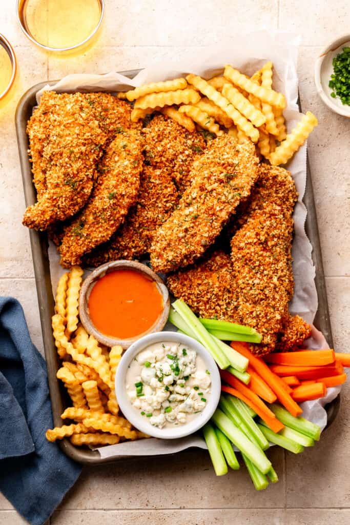 chicken tenders, fries, blue cheese, veggies, and buffalo sauce on sheet pan lined with parchment