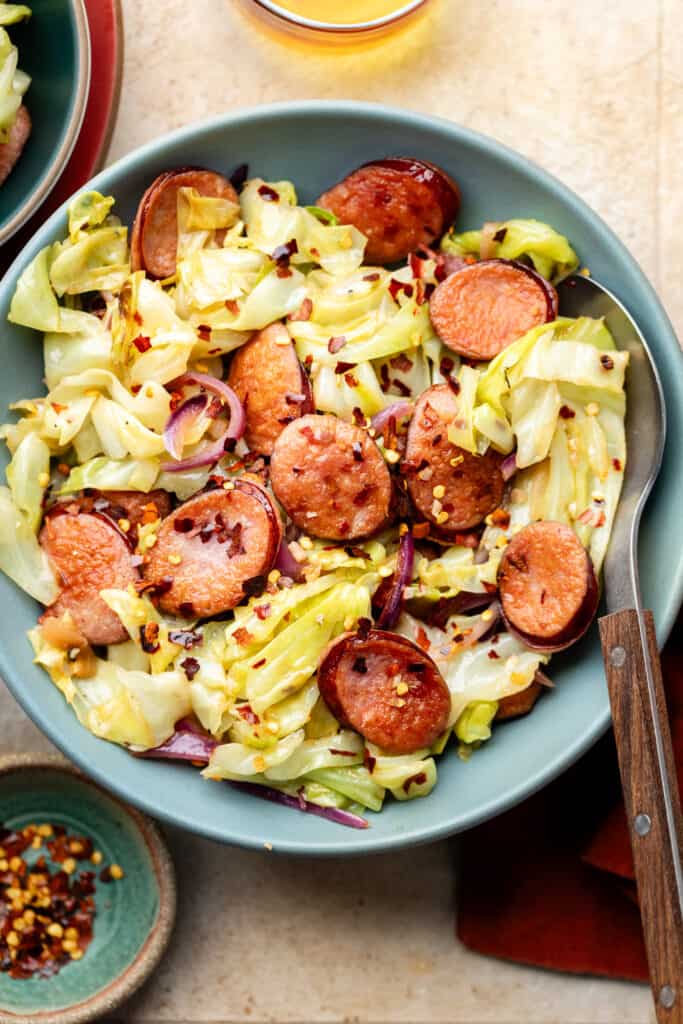 sausage and cabbage in blue bowl with spoon