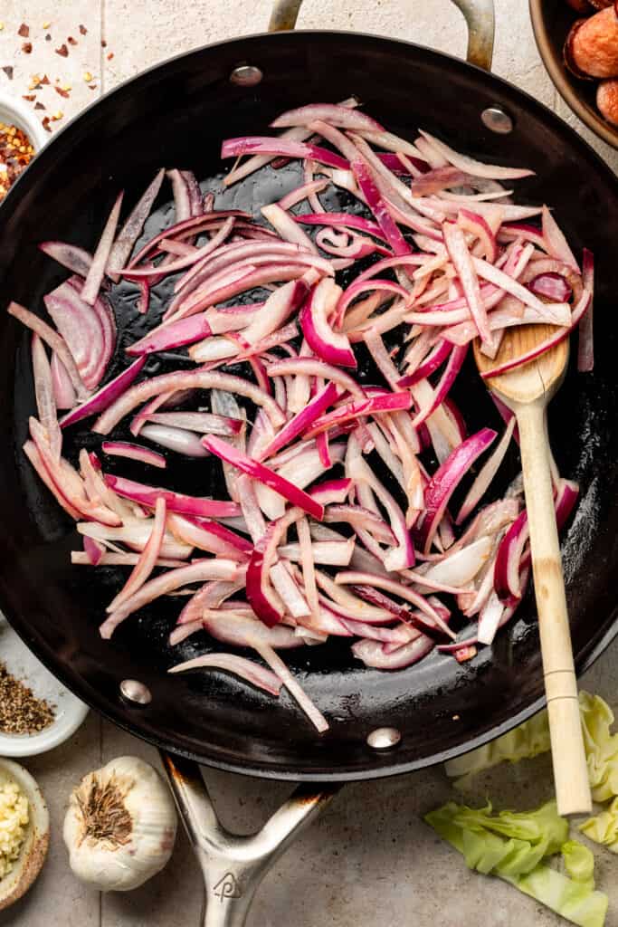 sliced red onion being sautéed in skillet