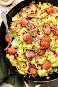 cabbage and sausage in skillet with fork