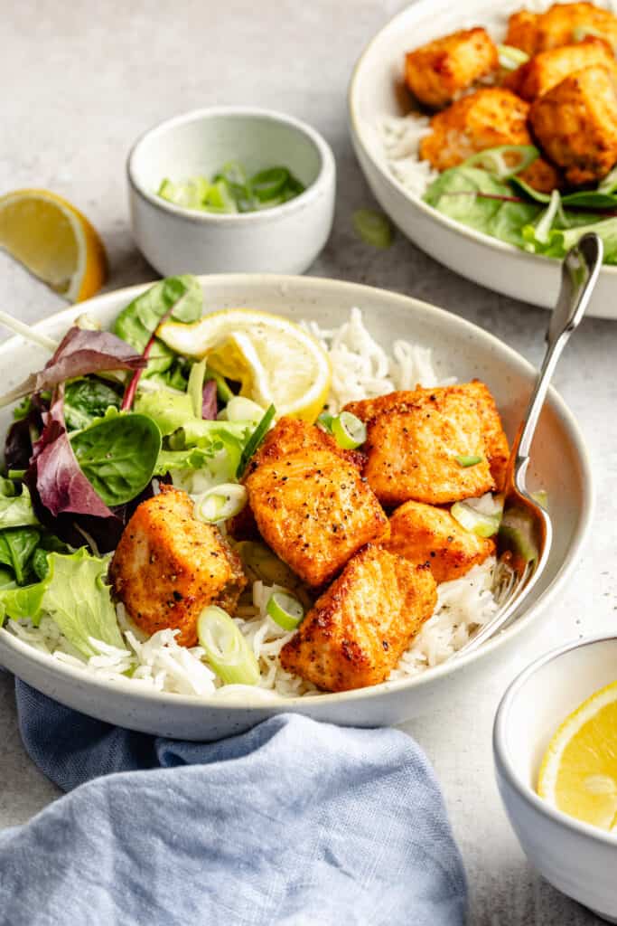 salmon bites over rice with greens in a bowl