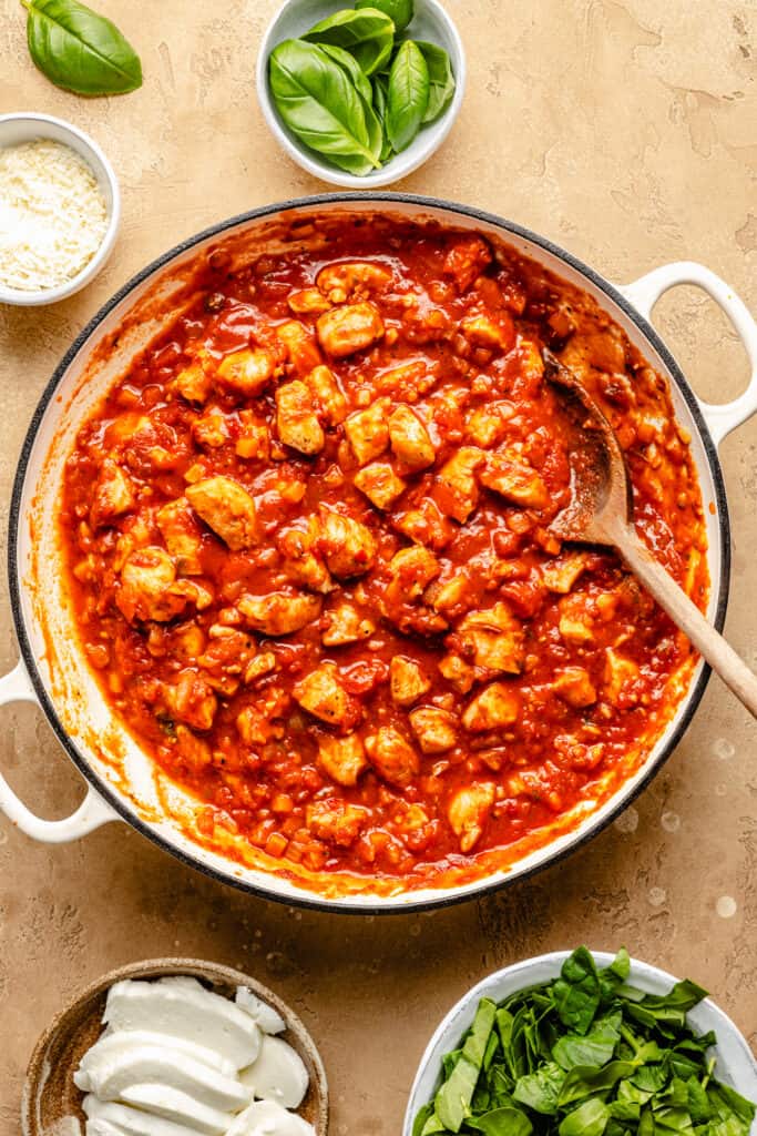 marinara sauce with chicken in skillet with spoon