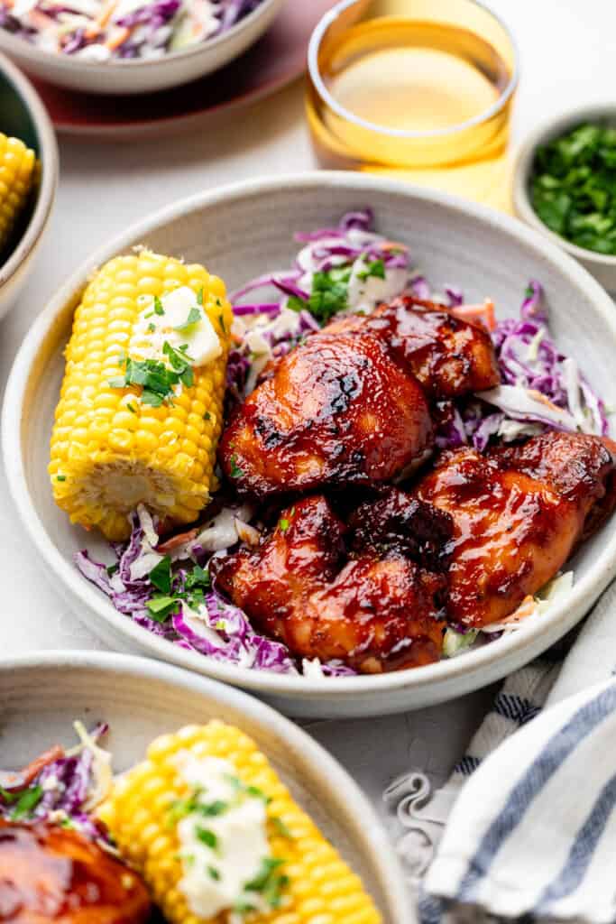 chicken thighs in bowl with corn and coleslaw