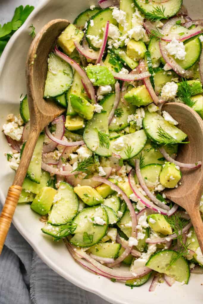 cucumber feta salad in bowl with wooden spoons