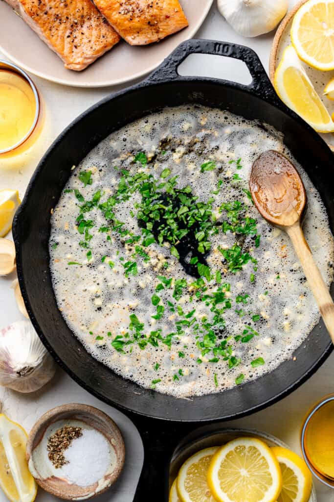 butter, garlic, and herbs in cast iron skillet with wooden spoon