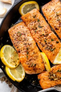 salmon in cast iron skillet with sliced lemons