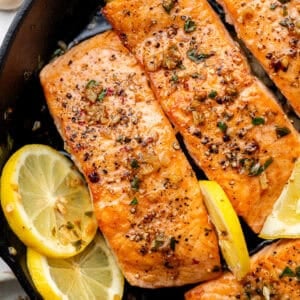 salmon in cast iron skillet with sliced lemons