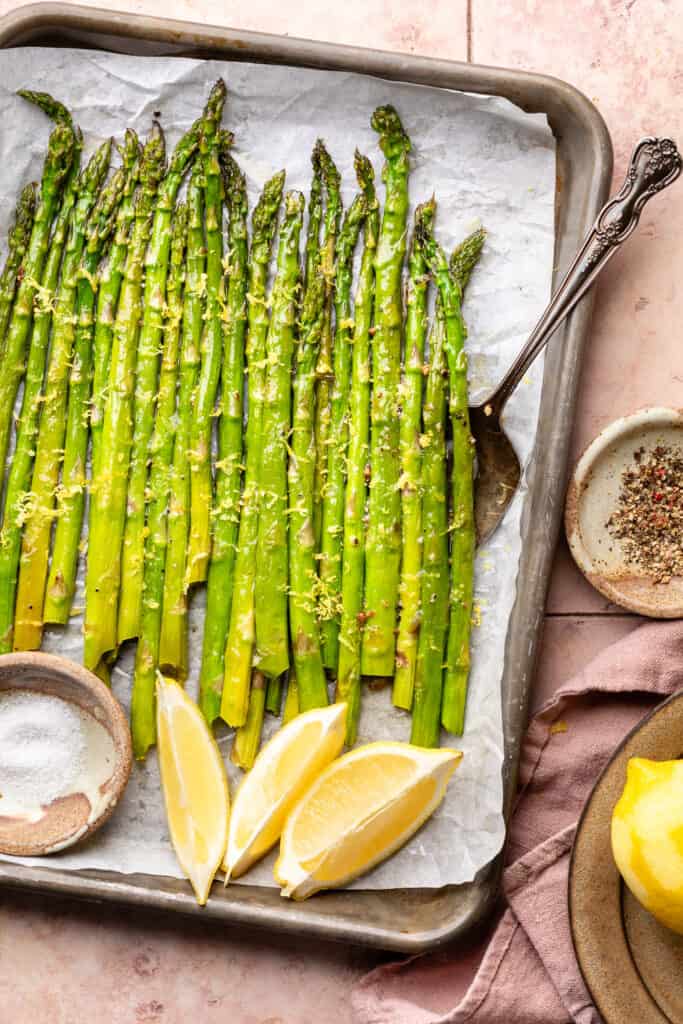 cooked asparagus on sheet pan with lemon zest