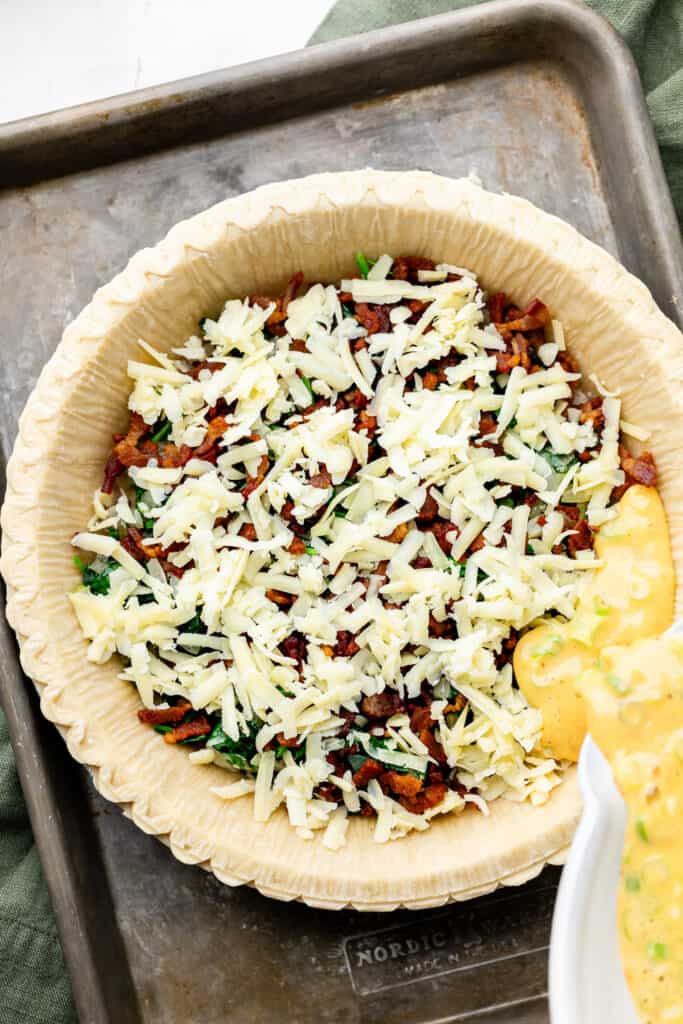 egg being poured over quiche ingredients