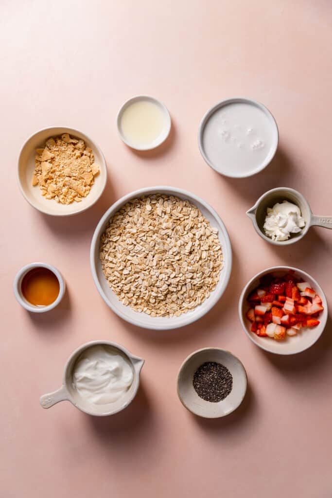 strawberry cheesecake overnight oats ingredients in small bowls