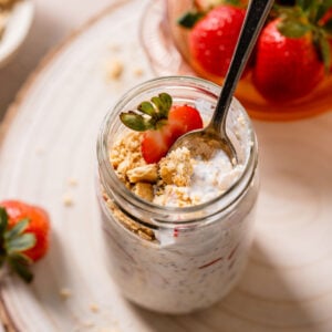 strawberry cheesecake overnight oats in glass mason jar with spoon