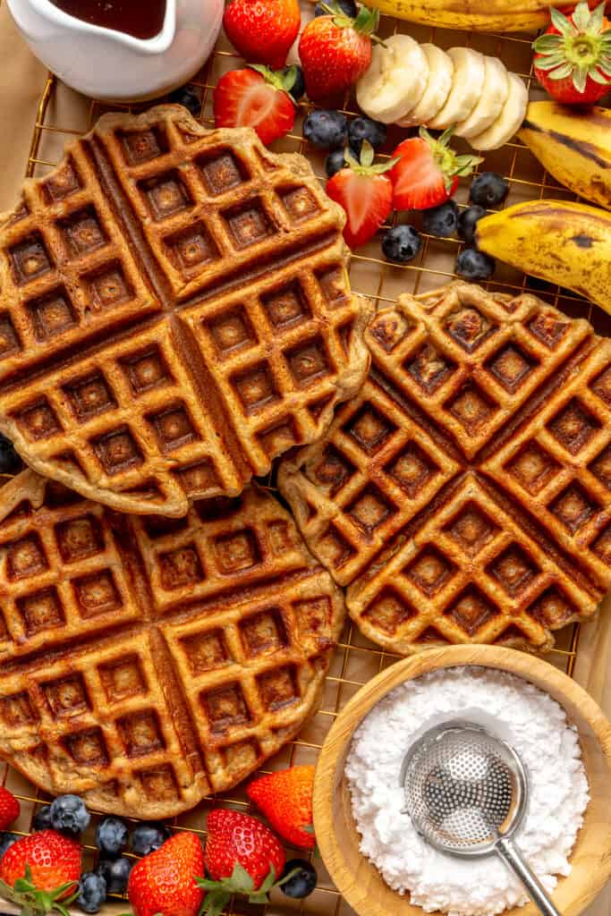 waffles on parchment paper with fruit and powdered sugar