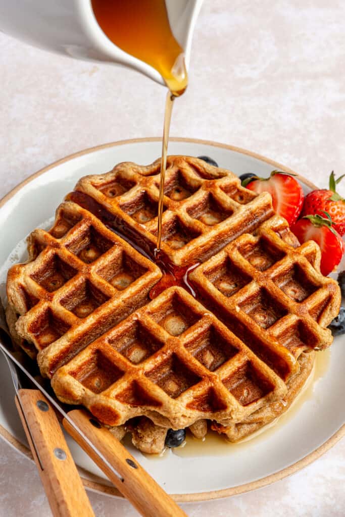 maple syrup being poured over waffle