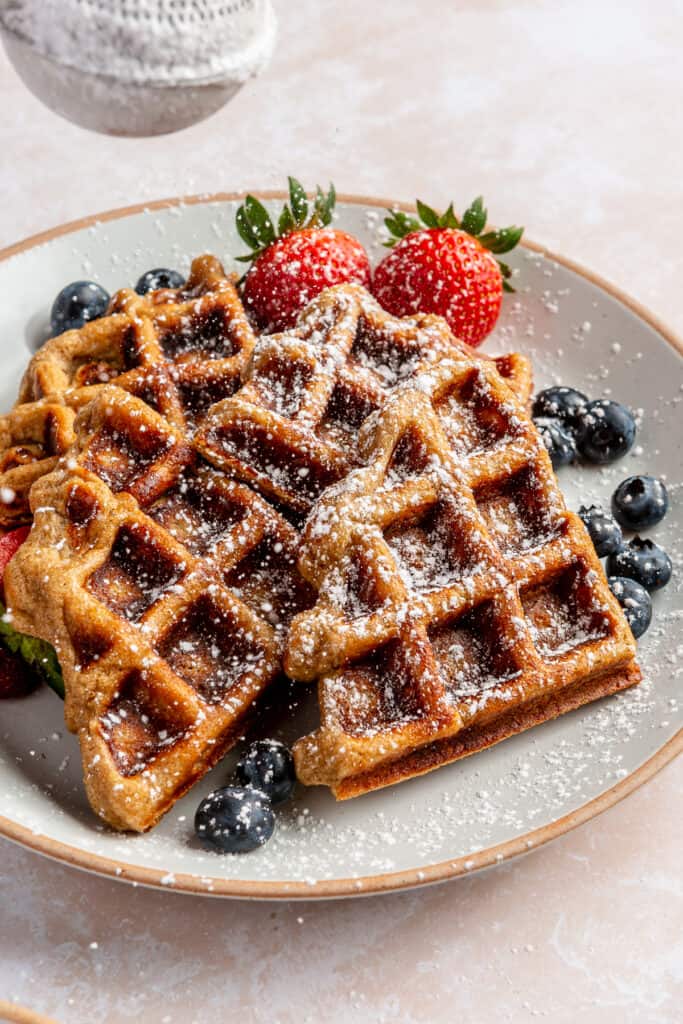 waffles on plate with powdered sugar and fresh fruit