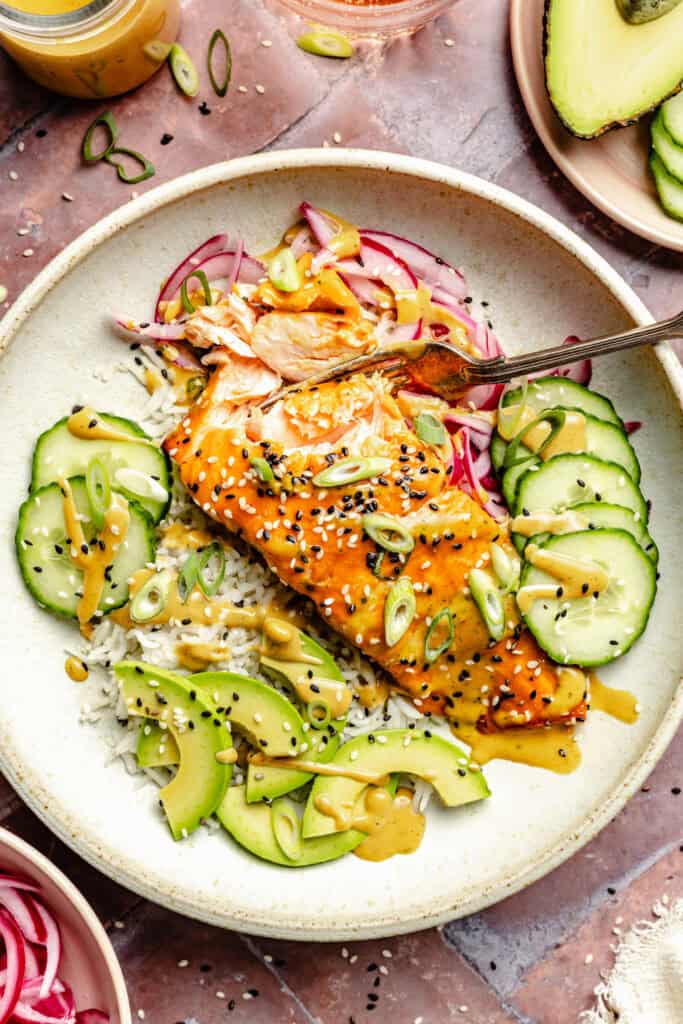 miso glazed salmon with rice and veggies and cashew dressing in white bowl