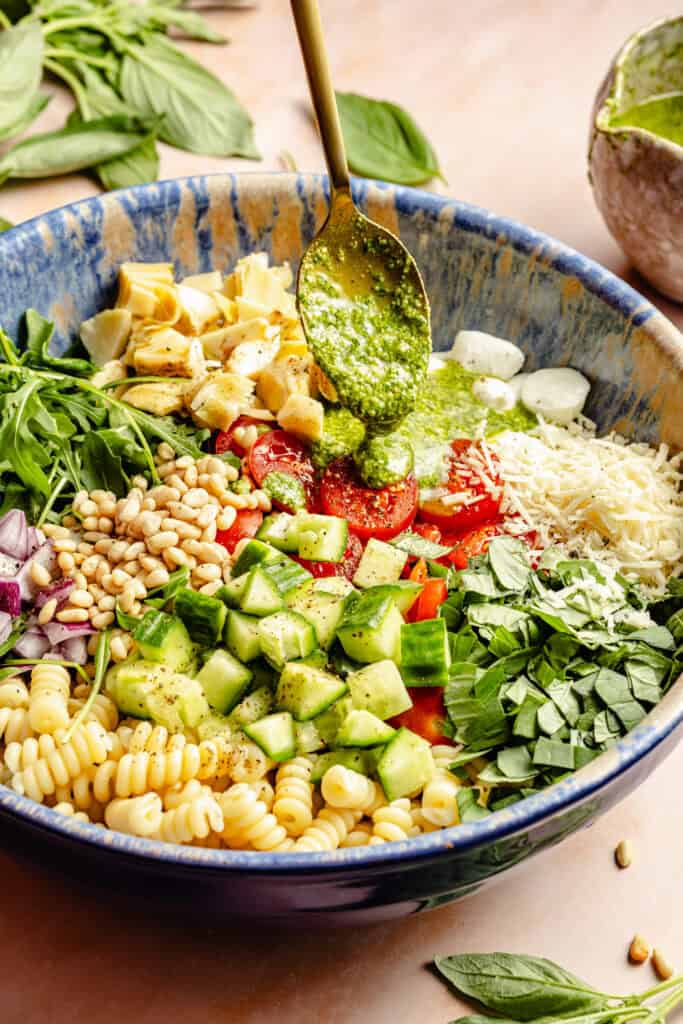 pesto pasta salad ingredients in large bowl and pesto dressing be drizzled over
