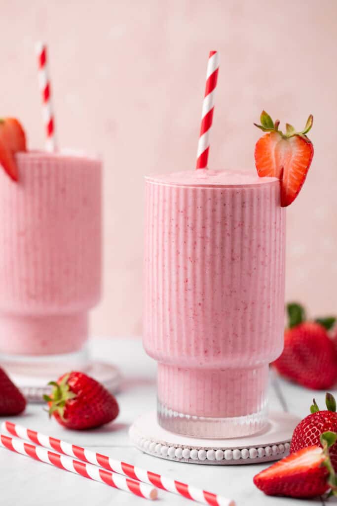 two glasses of strawberry smoothies with straws