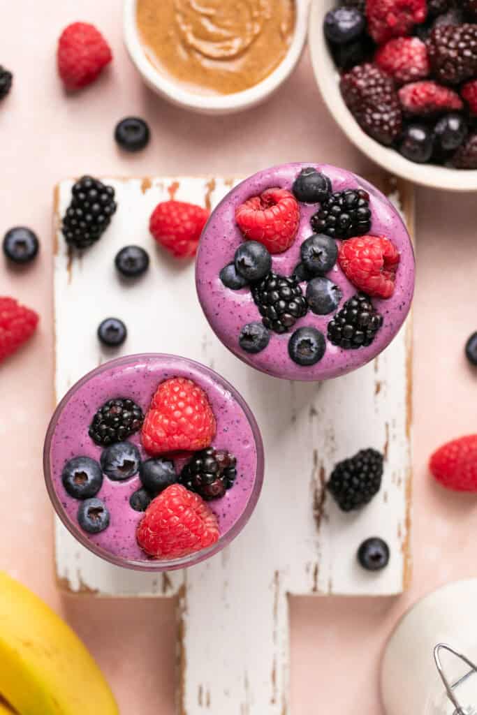 two smoothies on cutting board topped with berries