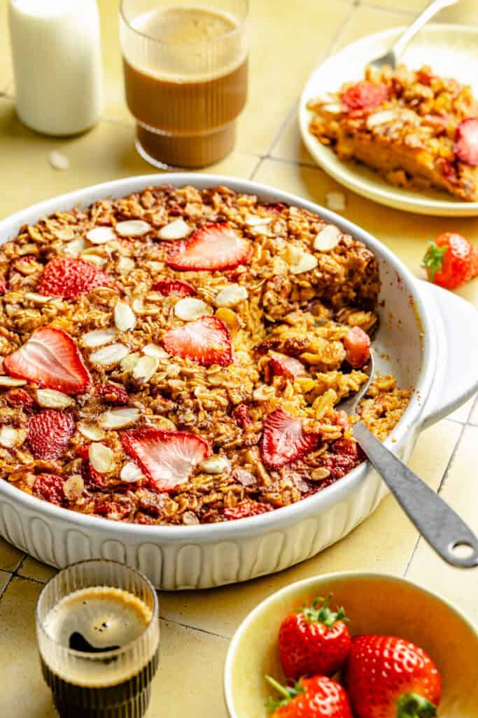 strawberry baked oatmeal in baking dish with serving dish 