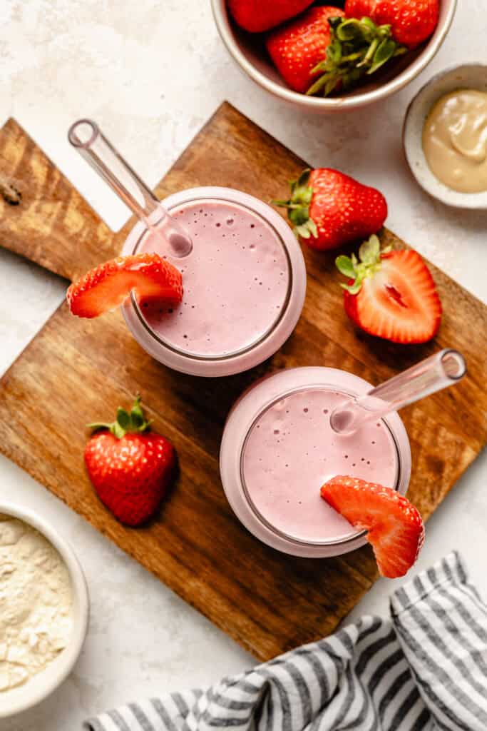 strawberry protein shake in glass topped with strawberry