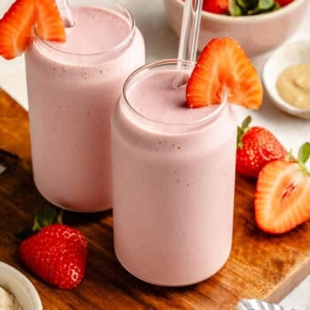 strawberry protein shake in glass topped with strawberry