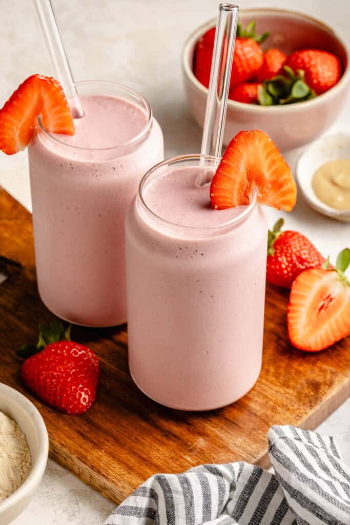 strawberry protein shake in glass topped with strawberry